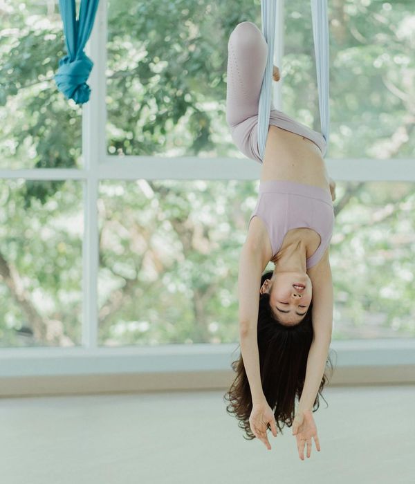 Person stretching gracefully in a sunlit studio, showing flexibility.